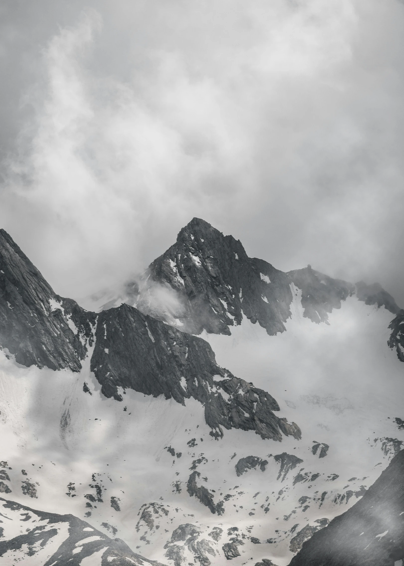 a large mountain covered in snow under cloudy skies