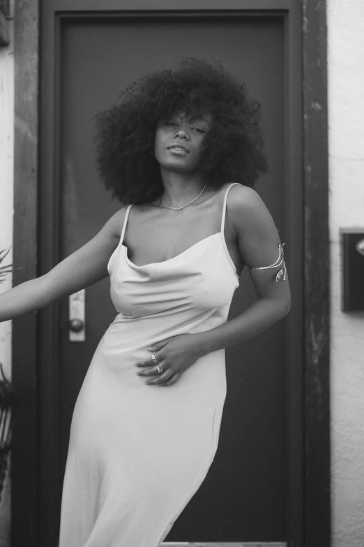 a woman poses outside of a door with her arms in the air