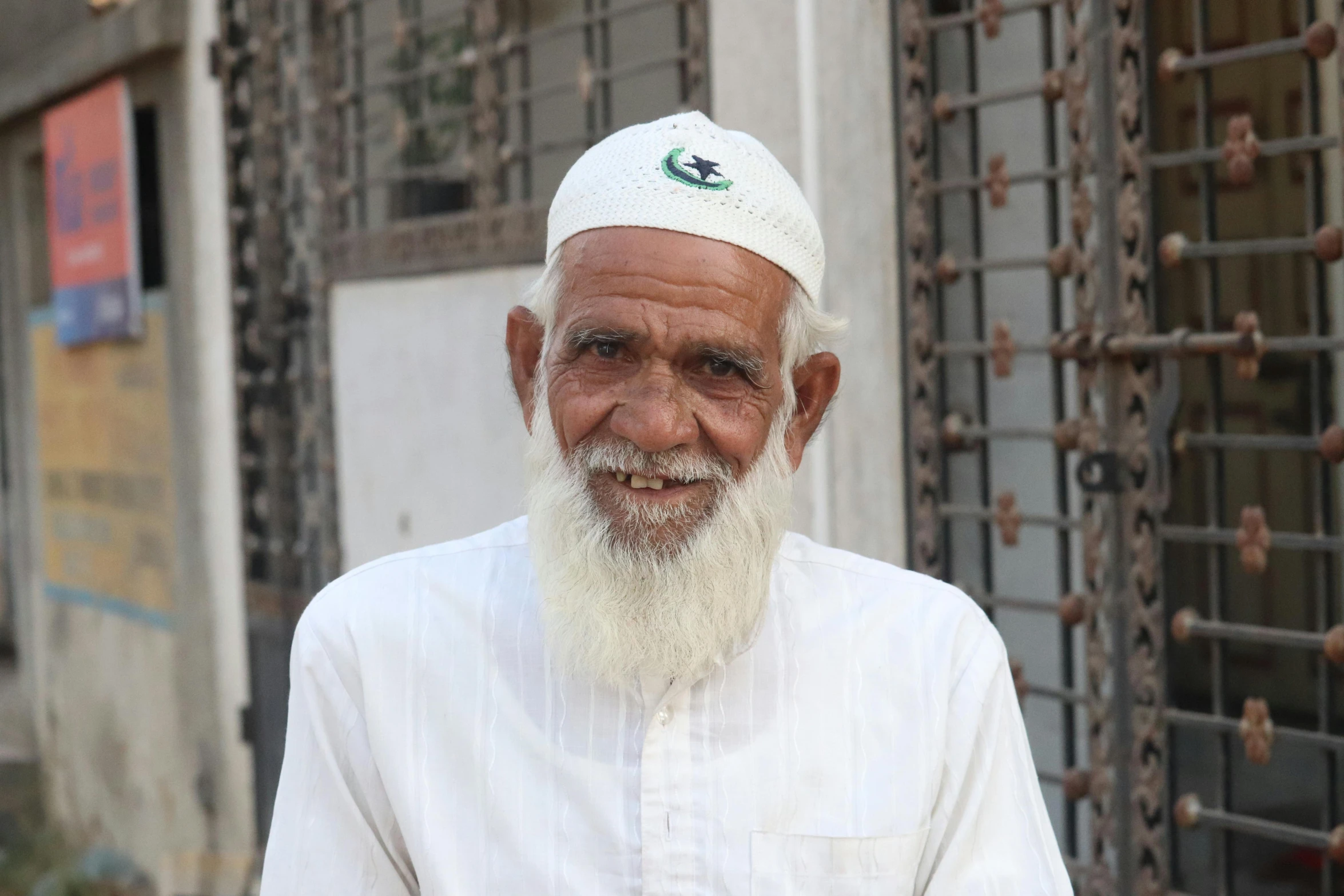 man with white beard, wearing a long white cap