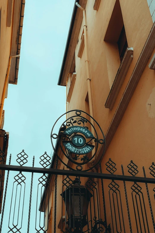 an iron gate holds a street sign up against the wall