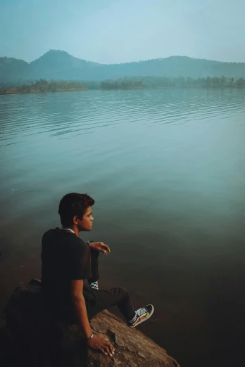 a person sitting on a rock with water