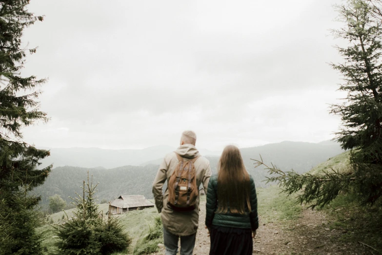 a man and woman walking along a dirt road in the mountains