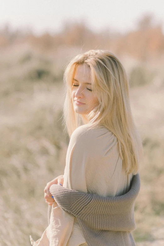 a woman stands in a field and smiles for the camera