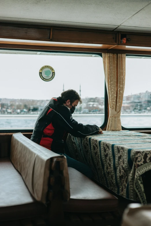 a woman sits at a window sill on a ferry