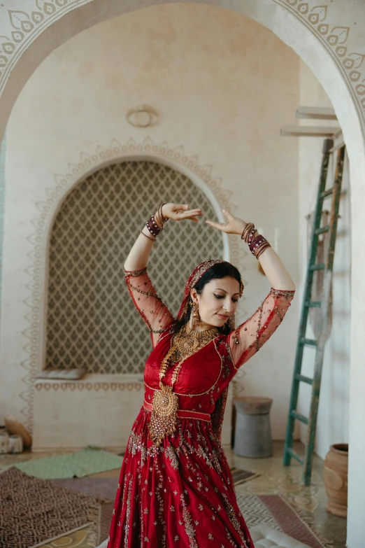 a woman in a red indian outfit is doing an art work