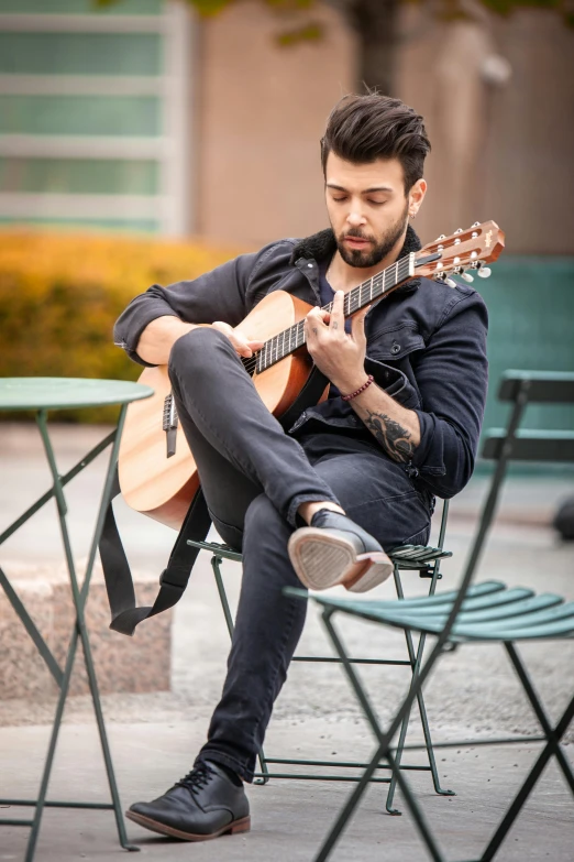 man sitting on chair holding a guitar near himself