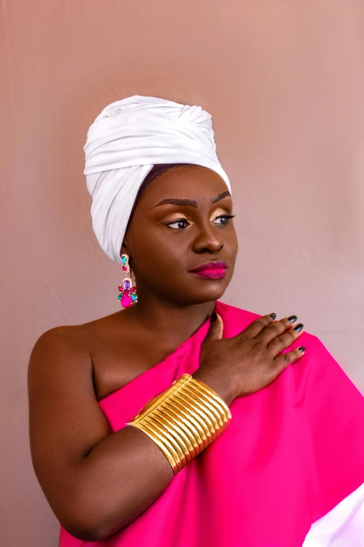 a woman wearing a pink dress with gold celets