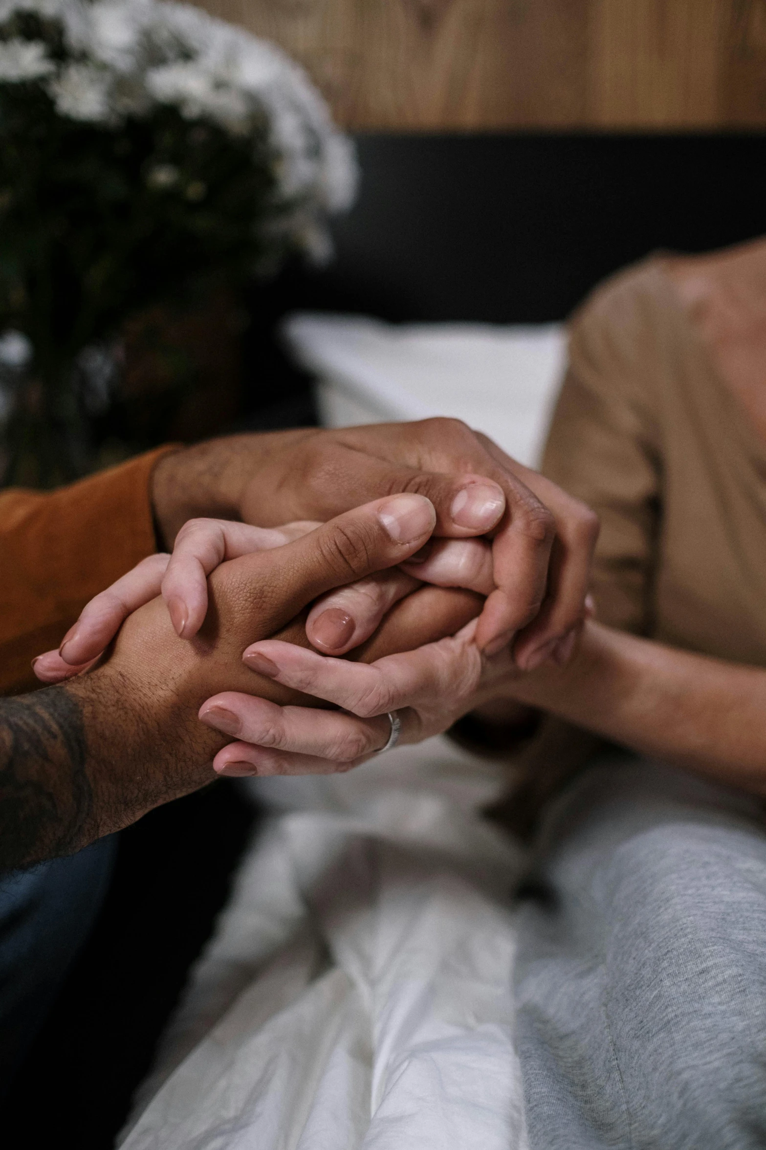 two people holding hands and sitting on a bed