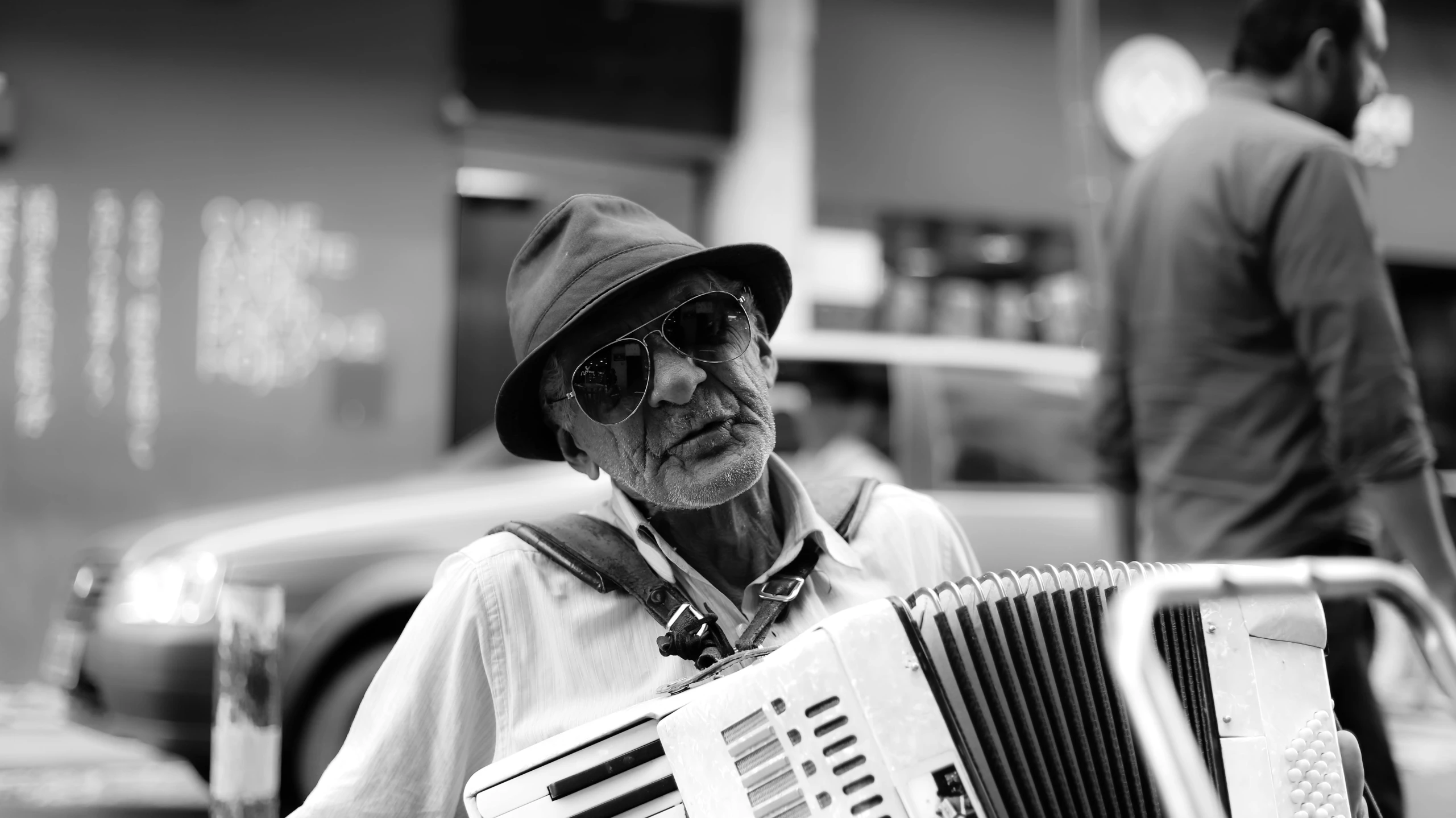 an older man sitting on the sidewalk playing an accordian