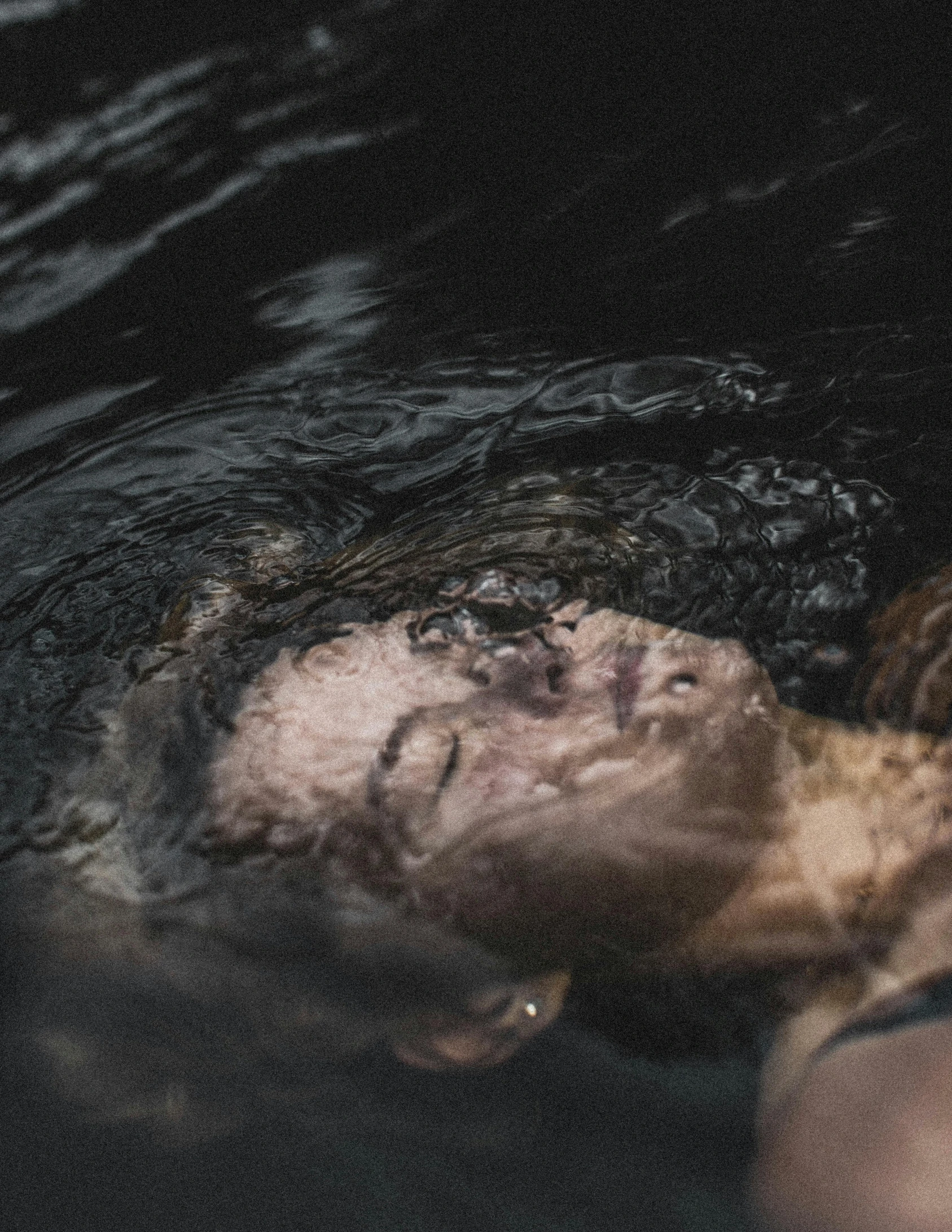 a man submerged in water, wearing a black shirt