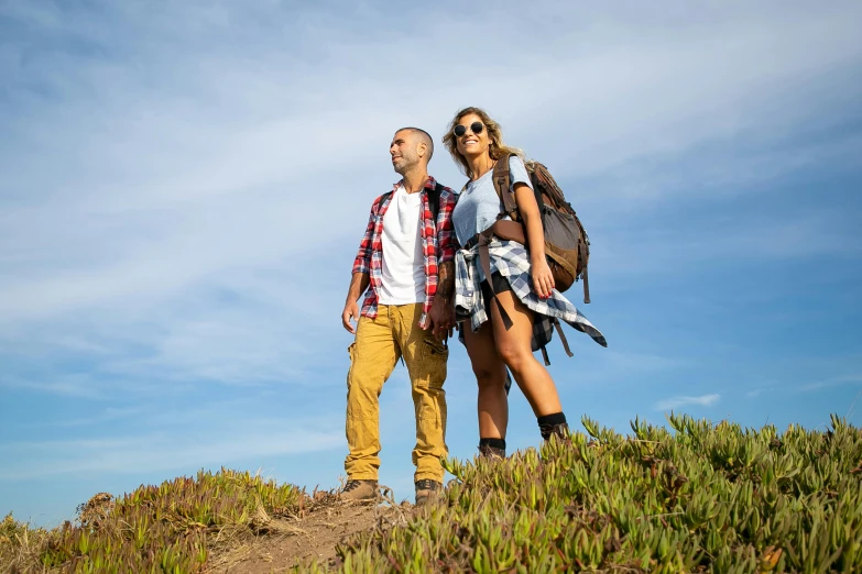 a man and woman with backpacks stand on top of a hill