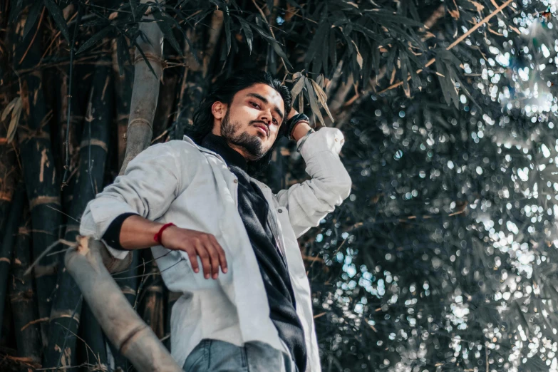 a man with his hands in his ears holding a cell phone to his ear while standing near some tall trees