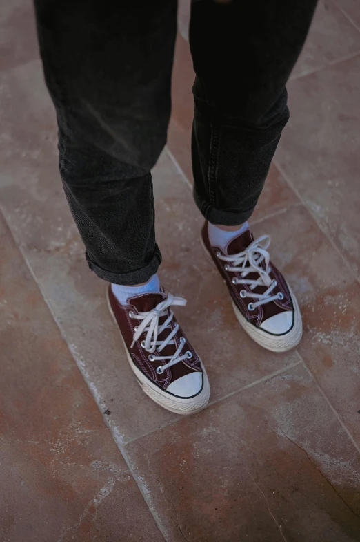 a person's legs wearing sneakers on tiled floor