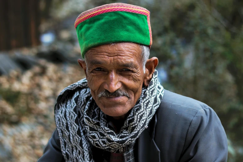 this old man is wearing a bright green head scarf and is posing for the camera