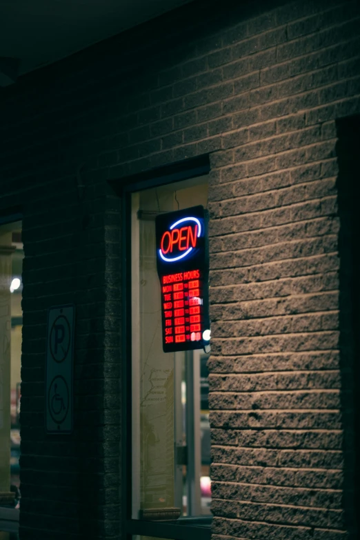 a lighted sign hangs from the side of a brick building