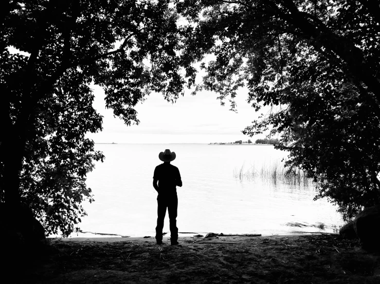 a man standing in front of trees by water