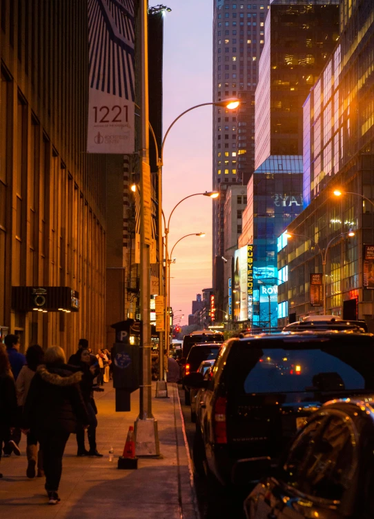 a busy sidewalk area near tall buildings at dusk