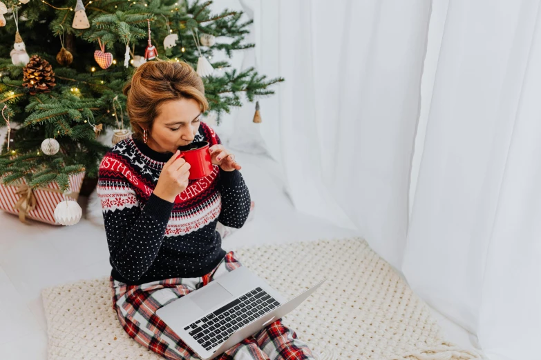 a woman with a coffee mug is sitting on the floor