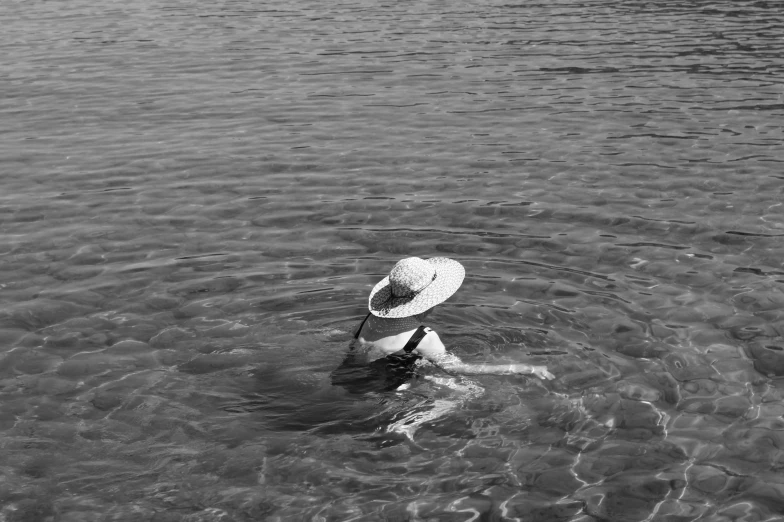 person in a hat wading through shallow water