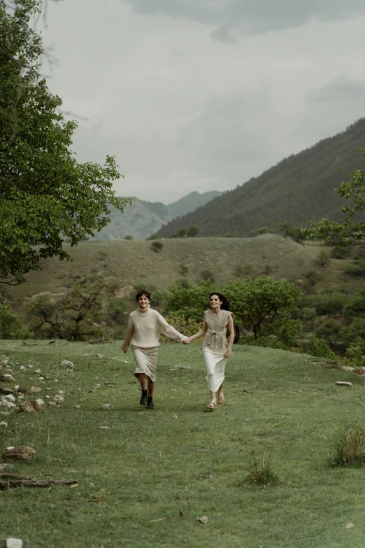 two people walk hand in hand through a field