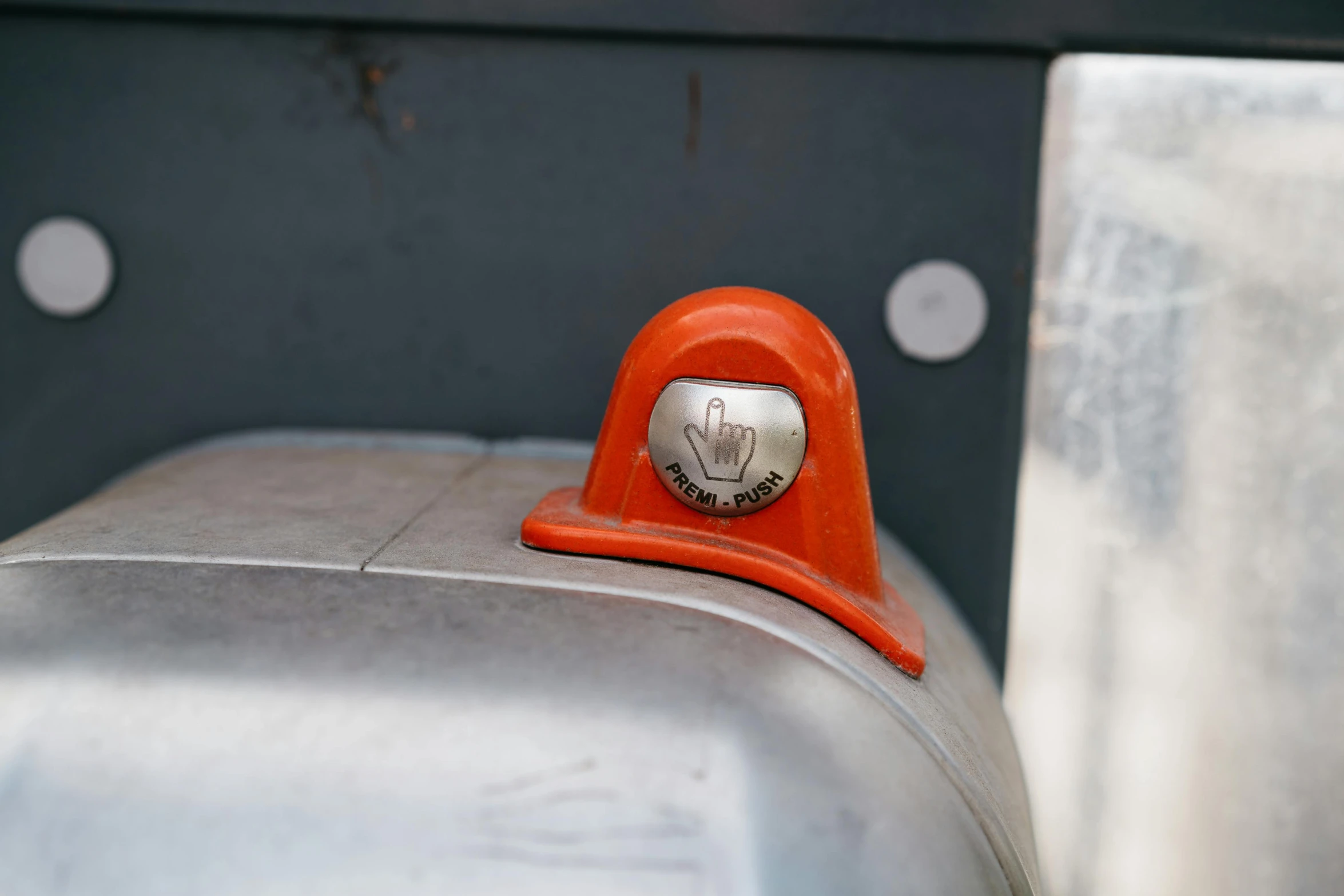 a red post with a metal base and silver and orange cover