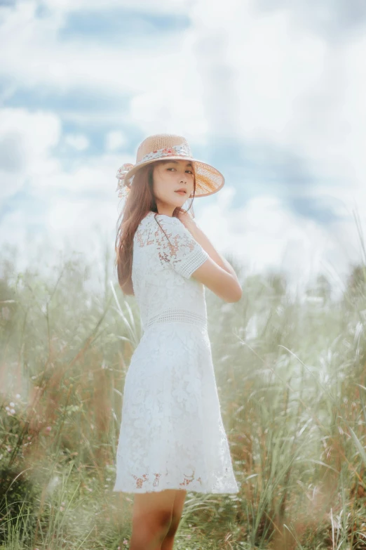 a girl standing in tall grass wearing a hat