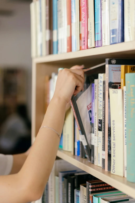 the person is putting together the books in the shelves