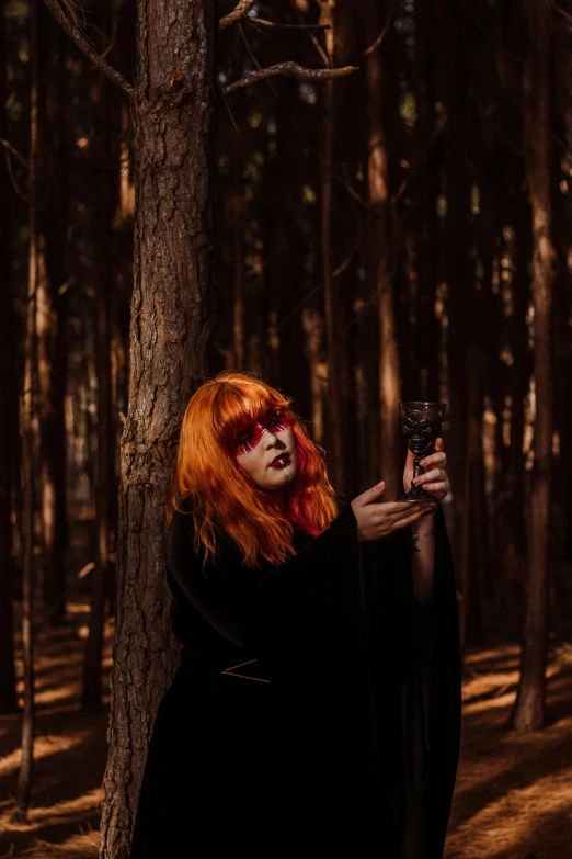 a red haired woman poses for the camera, with her hands in the air and her eyes closed, while wearing black