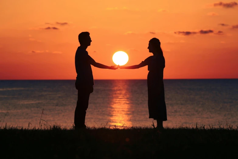 two people standing on top of a hill near the ocean