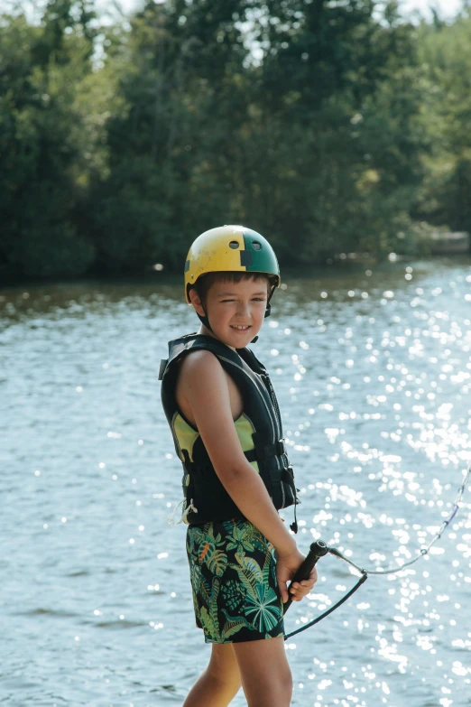 a boy in a life jacket is standing on the lake