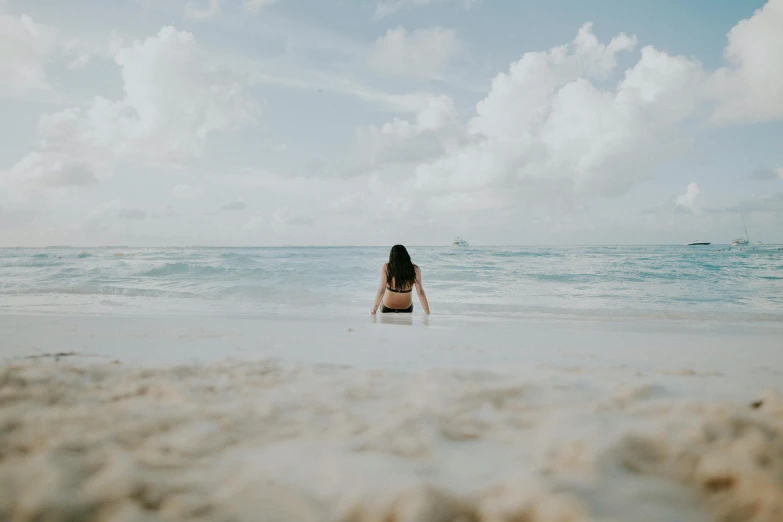 a woman is sitting on a beach in the sand