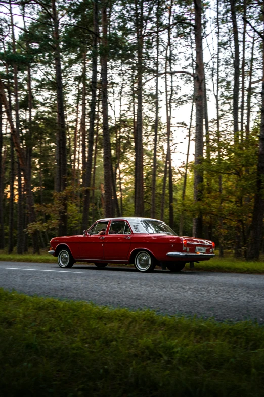 a red classic car parked in the middle of a road