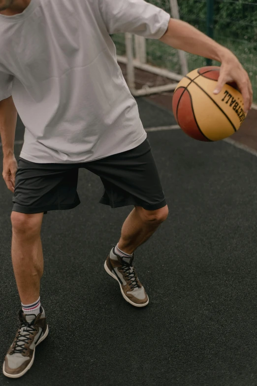 a man in white shirt with basketball on court