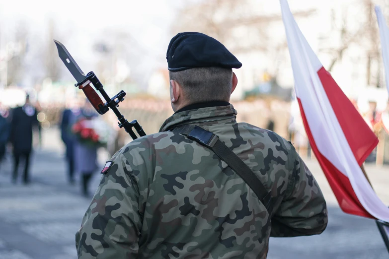 a soldier with a rifle and flag walking away from an event