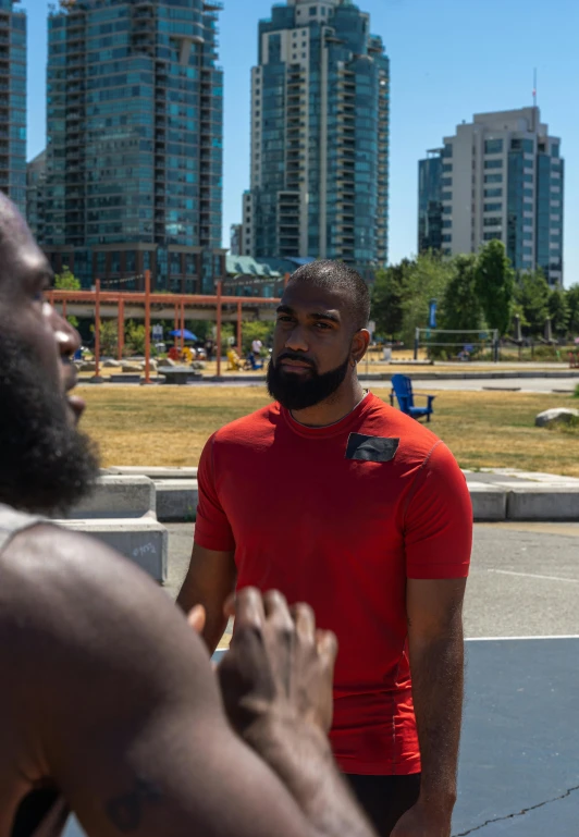 a man with a beard and a red shirt looks at another man in a red shirt