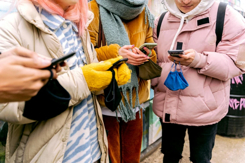 three people standing next to each other and looking at phones