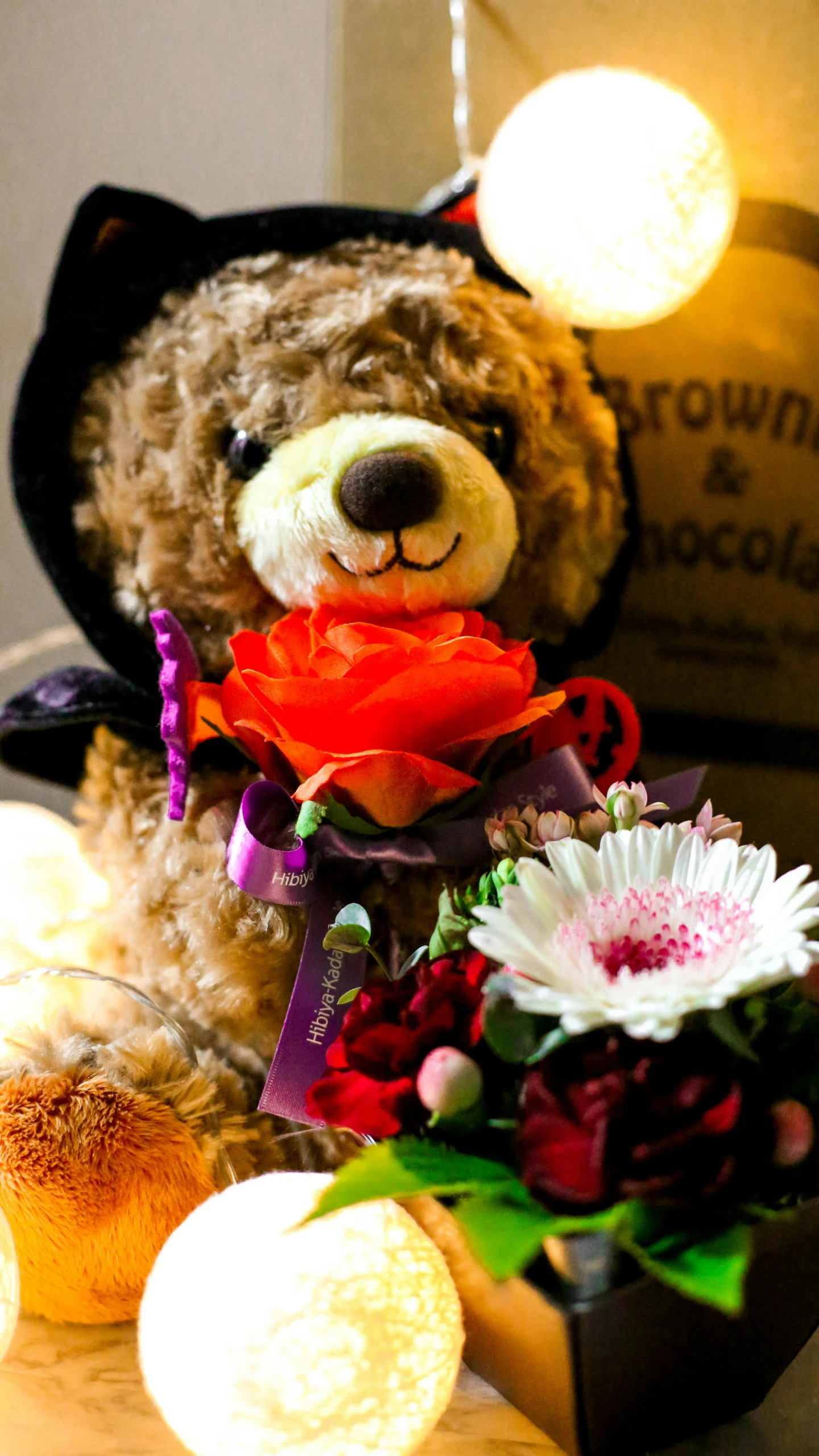 a teddy bear with some flowers and some lights