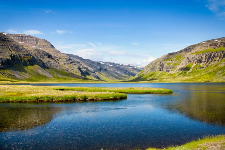 the view of a lake and grassy hills