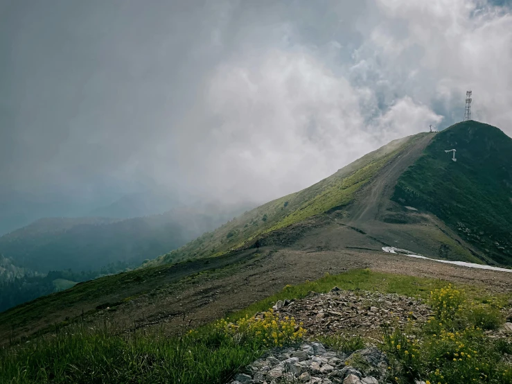 the top of a very tall mountain under a cloudy sky