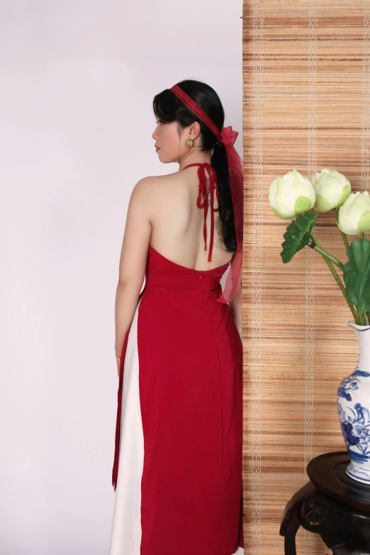 a woman wearing a red dress standing by a wall