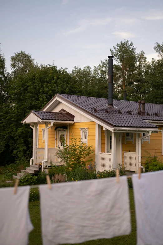 yellow house surrounded by clothes and trees outside