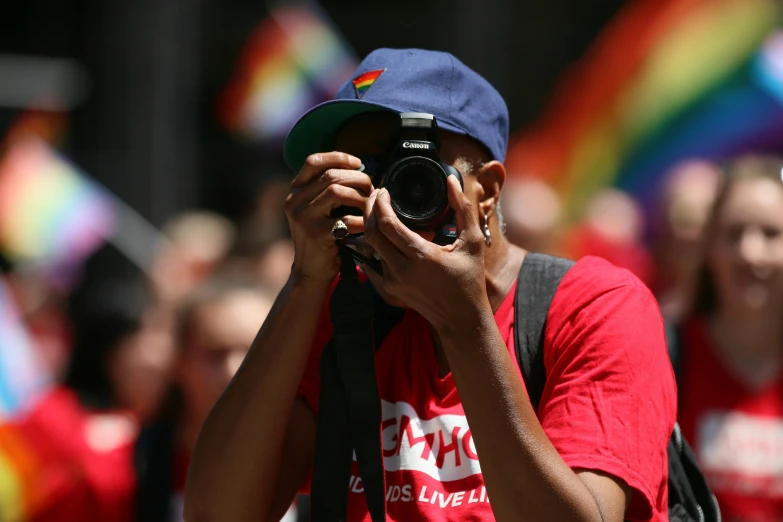 a man is taking a picture of a rainbow flag with a camera