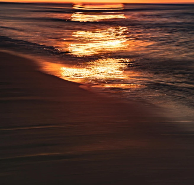 the sun shining over the water off a beach