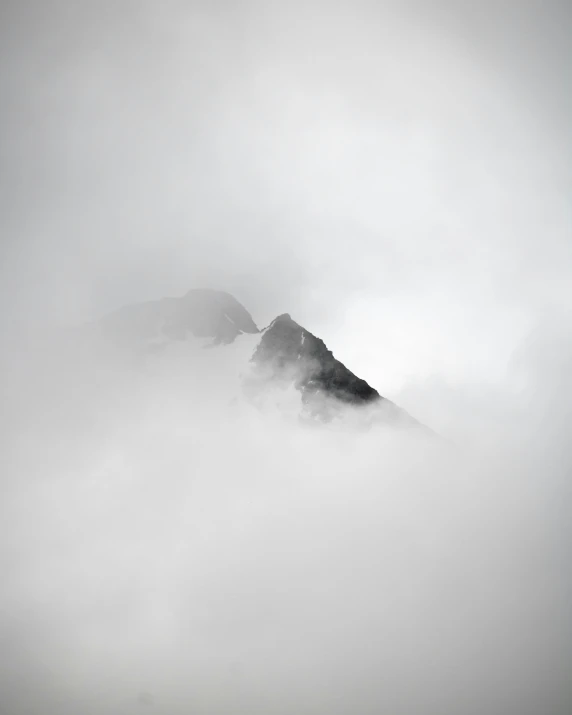 mountains covered in mist with one mountain surrounded by fog