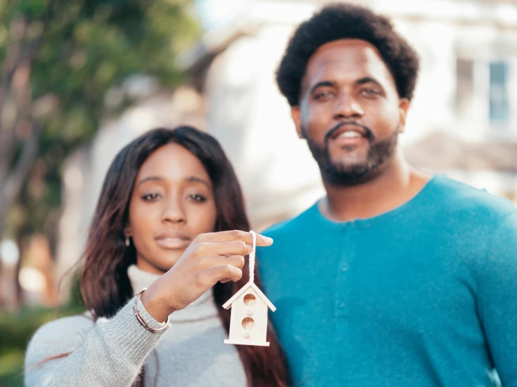 a couple holding a paper model of a house