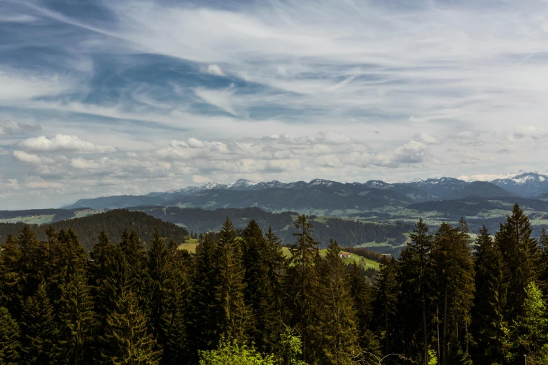 some white clouds are in the sky over a beautiful green valley