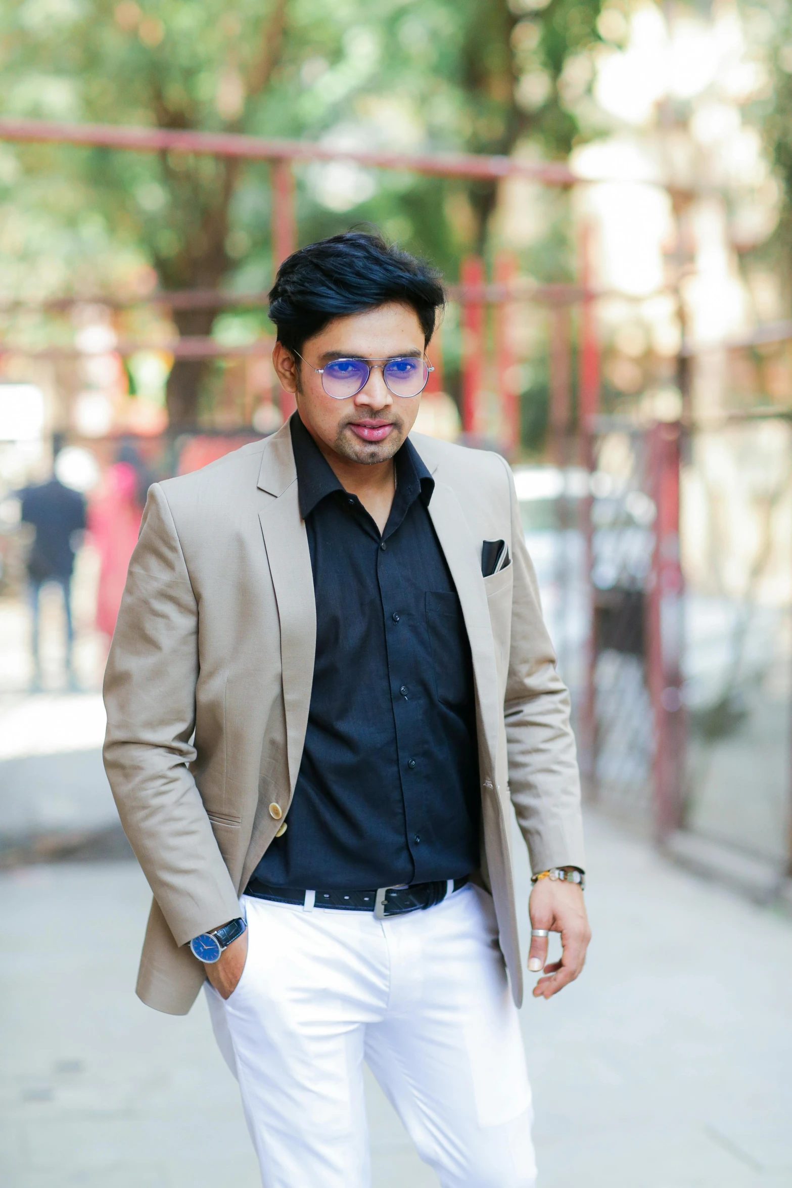 a man wearing glasses standing on the sidewalk