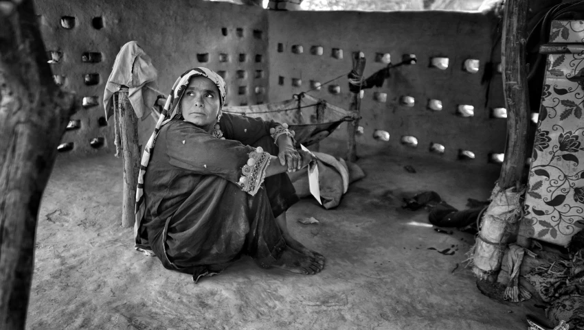 black and white pograph of an old woman sitting in the doorway