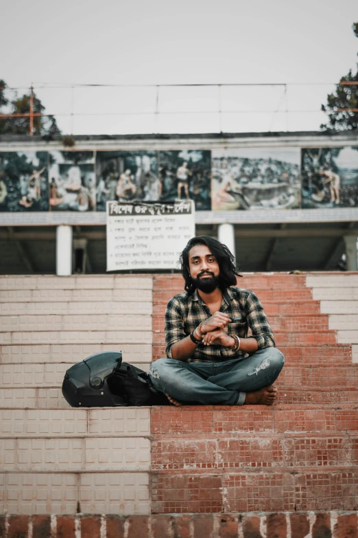 a man sitting on some steps wearing jeans