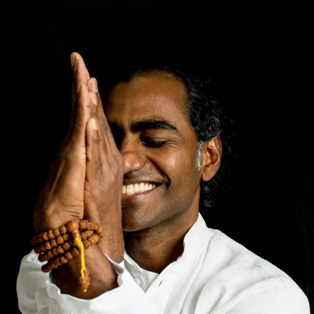 an indian man is smiling and holding his hands together